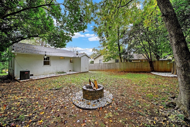 view of yard with central AC unit, an outdoor fire pit, and fence