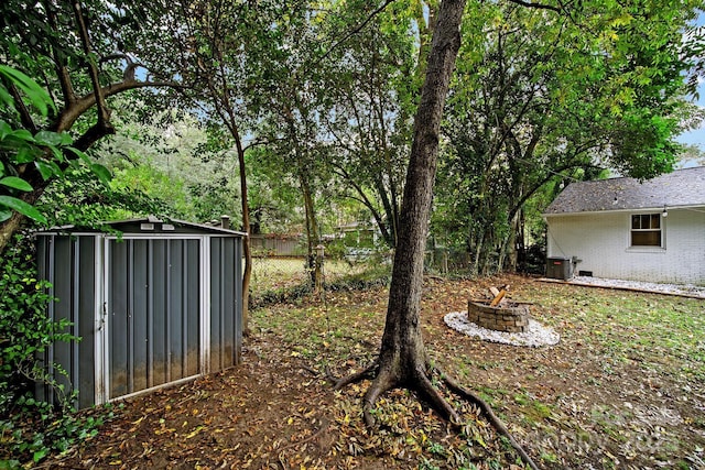 view of yard featuring an outbuilding, a fire pit, fence, and a shed