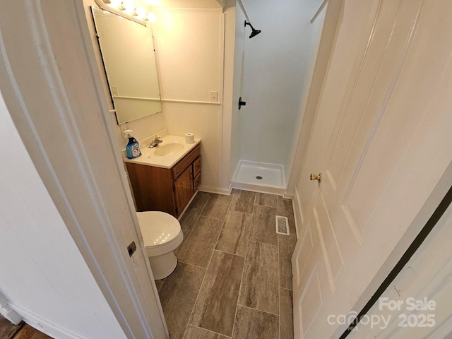 full bathroom featuring visible vents, a shower stall, wood tiled floor, toilet, and vanity