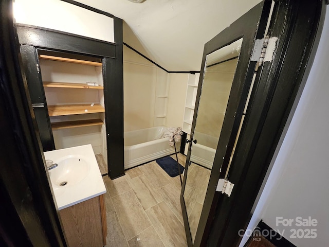 bathroom with shower / bathtub combination, vanity, and vaulted ceiling