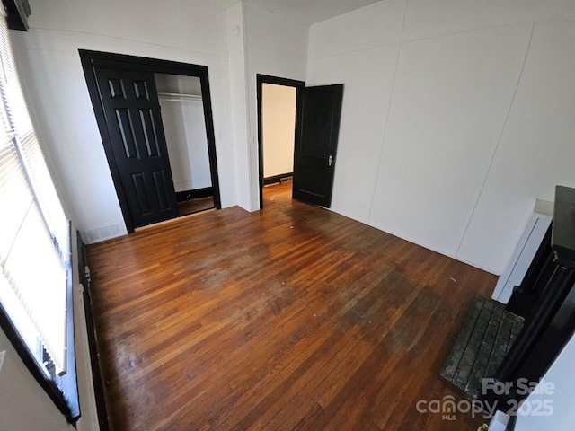 unfurnished bedroom with visible vents, multiple windows, and dark wood-type flooring