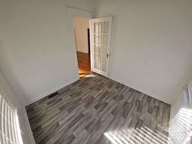 unfurnished room with dark wood-type flooring, baseboards, and visible vents