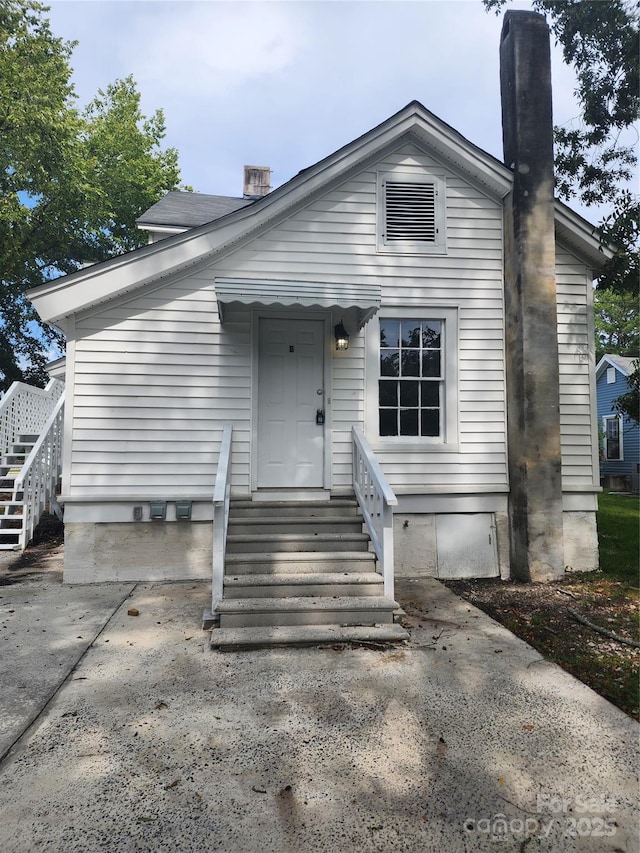 view of front of house featuring entry steps and a chimney