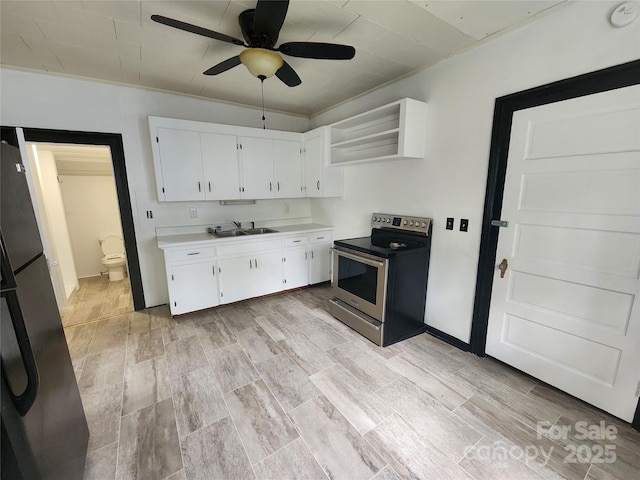 kitchen with open shelves, stainless steel electric range oven, freestanding refrigerator, white cabinetry, and a sink