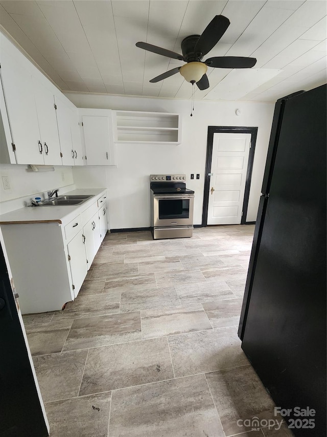 kitchen with electric range, a sink, freestanding refrigerator, white cabinets, and light countertops