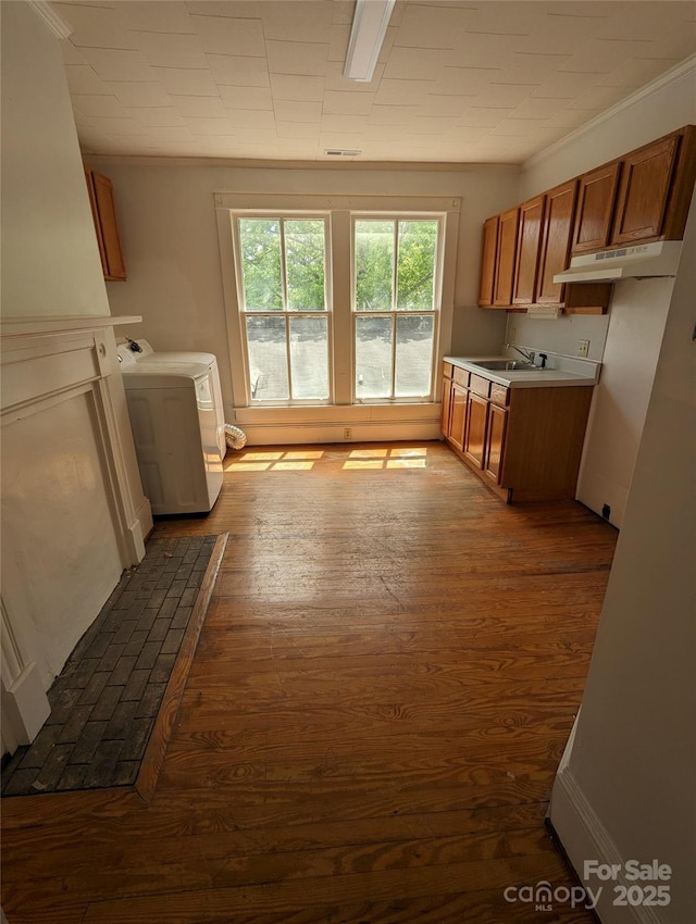 clothes washing area featuring dark wood-style floors, washer / dryer, crown molding, and a sink