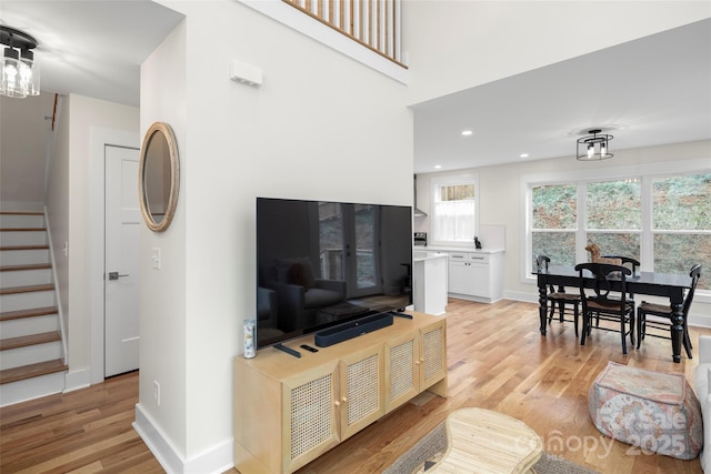 living room with recessed lighting, stairs, light wood-type flooring, and baseboards