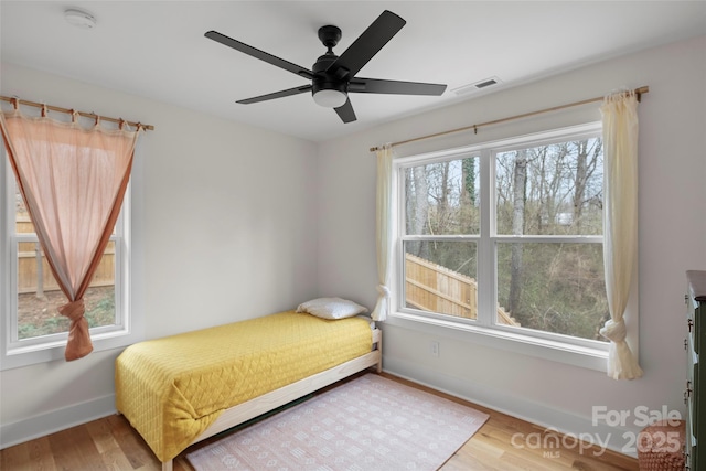 bedroom featuring a ceiling fan, visible vents, wood finished floors, and baseboards