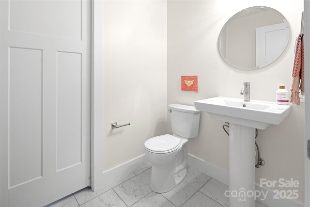 half bathroom featuring baseboards, toilet, and marble finish floor