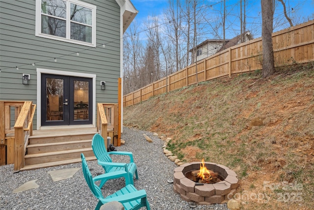 view of yard with french doors, a fire pit, and fence