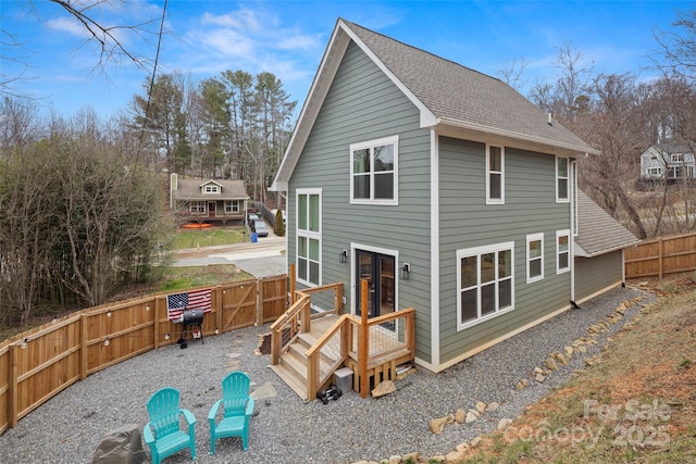 back of house with a shingled roof, a fenced backyard, and a gate