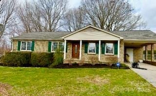 view of front facade featuring a front lawn, a carport, and driveway