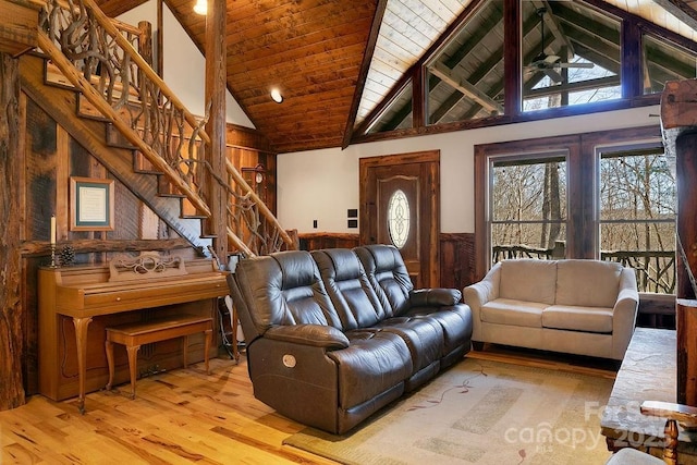 living area with stairway, wood finished floors, high vaulted ceiling, wainscoting, and wooden ceiling