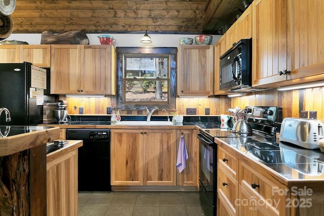 kitchen with light tile patterned floors, black appliances, tile counters, and a sink