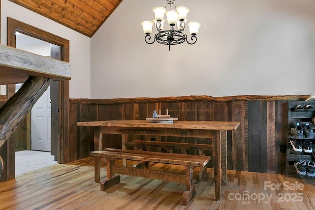 dining area featuring light wood-type flooring, an inviting chandelier, wainscoting, lofted ceiling, and wood ceiling