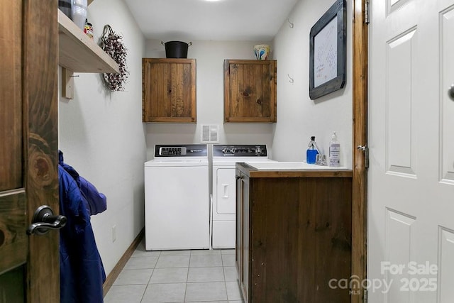 laundry room featuring separate washer and dryer, light tile patterned flooring, cabinet space, and baseboards