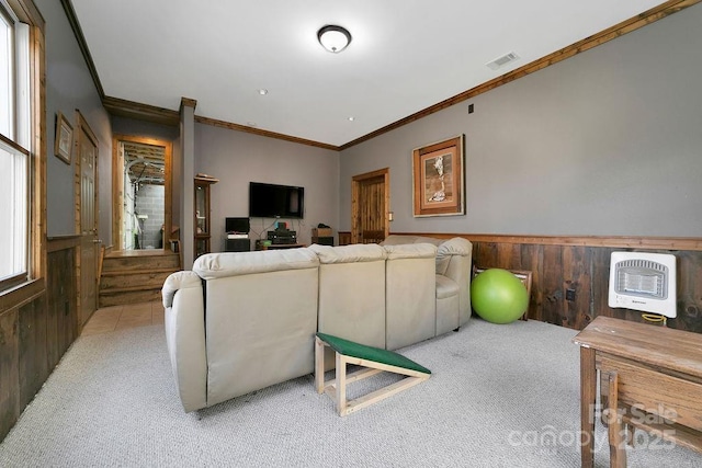 living area with a wainscoted wall, visible vents, light colored carpet, and wooden walls