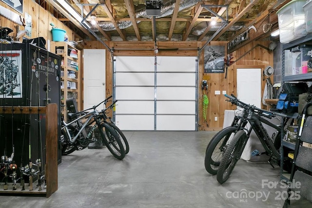 garage with a garage door opener and wood walls