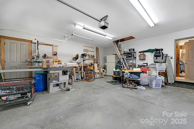 garage featuring a workshop area, a garage door opener, and freestanding refrigerator