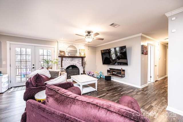 living room featuring visible vents, wood finished floors, french doors, crown molding, and a brick fireplace