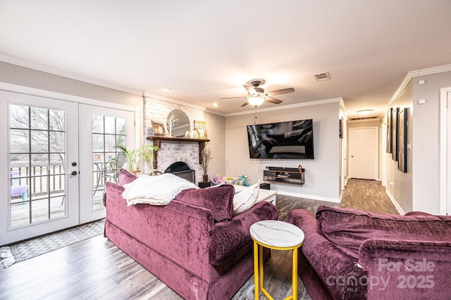 living room featuring visible vents, crown molding, a fireplace, french doors, and wood finished floors