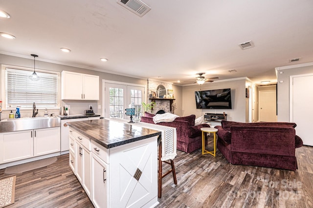 kitchen with dark countertops, visible vents, dark wood-type flooring, and a sink