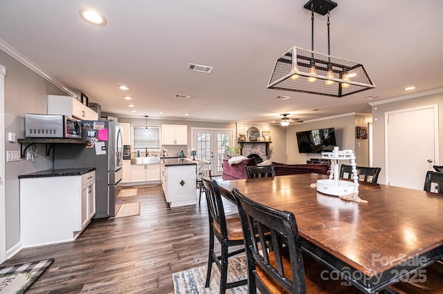 dining area featuring visible vents, dark wood finished floors, recessed lighting, a fireplace, and crown molding