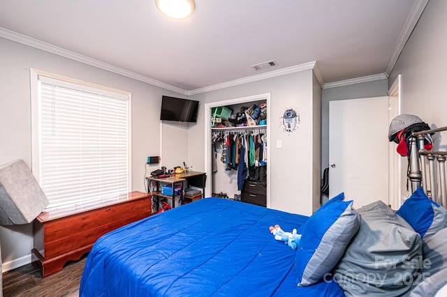 bedroom with visible vents, wood finished floors, a closet, crown molding, and baseboards