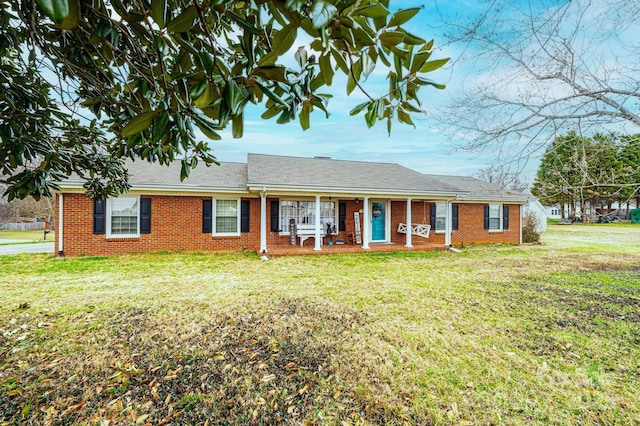 single story home featuring a front yard, a porch, and brick siding