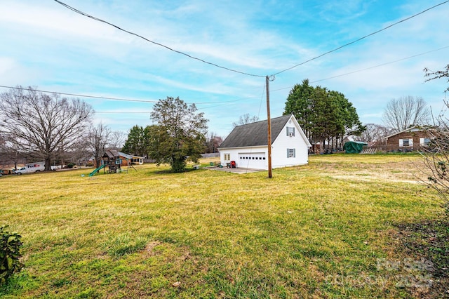 view of yard with a detached garage, an outbuilding, and a playground