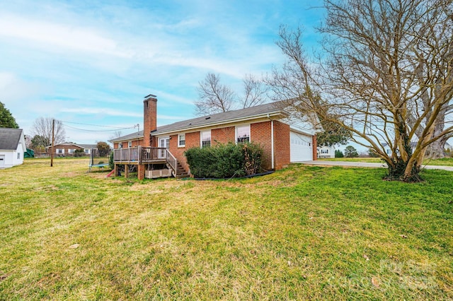 rear view of property featuring a wooden deck, a chimney, a garage, a lawn, and brick siding