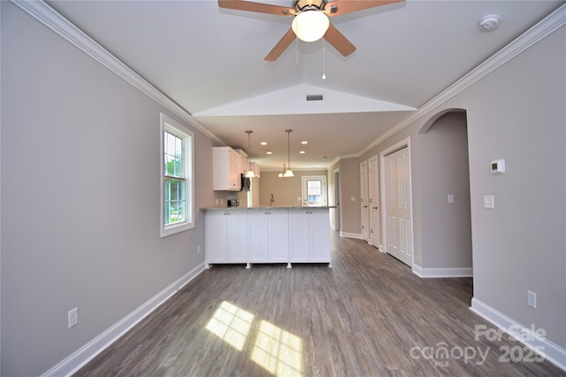 unfurnished living room with dark wood-style floors, baseboards, lofted ceiling, arched walkways, and ornamental molding