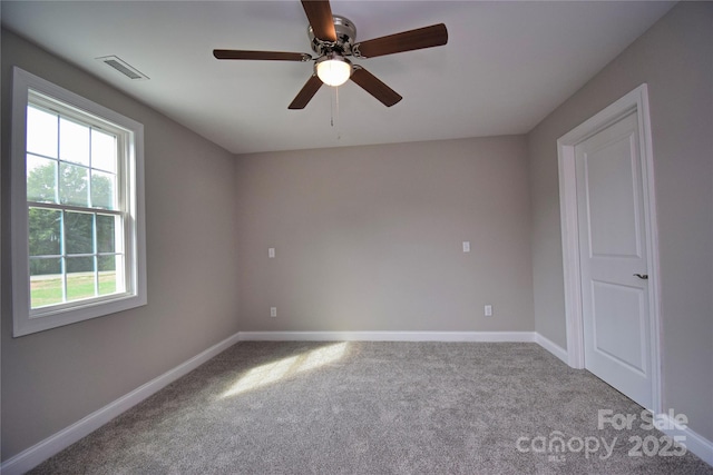 carpeted empty room featuring baseboards, visible vents, and ceiling fan