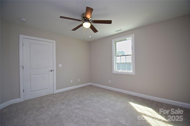 carpeted empty room featuring visible vents, baseboards, and a ceiling fan