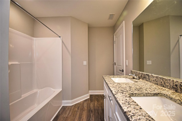 bathroom with visible vents, baseboards, wood finished floors,  shower combination, and a sink