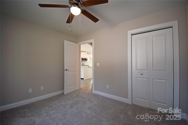 unfurnished bedroom with a closet, baseboards, carpet floors, and ceiling fan