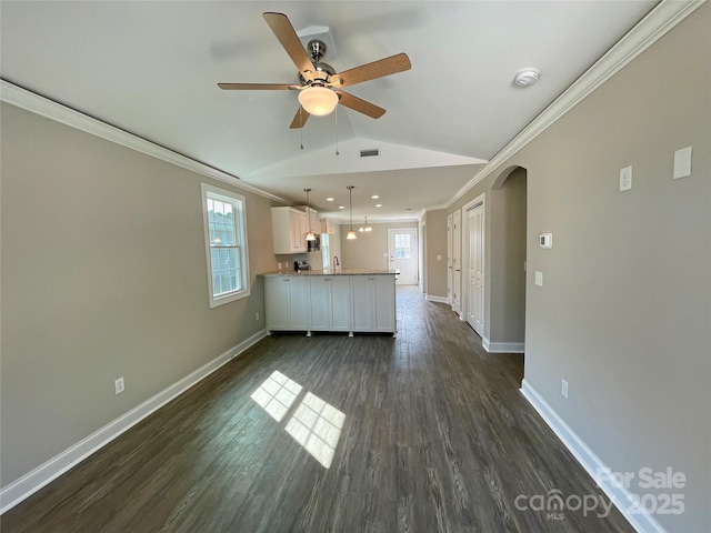 unfurnished living room featuring arched walkways, dark wood-style floors, crown molding, and vaulted ceiling