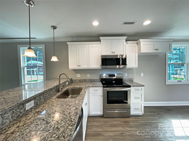 kitchen with a sink, dark wood-type flooring, appliances with stainless steel finishes, white cabinetry, and crown molding