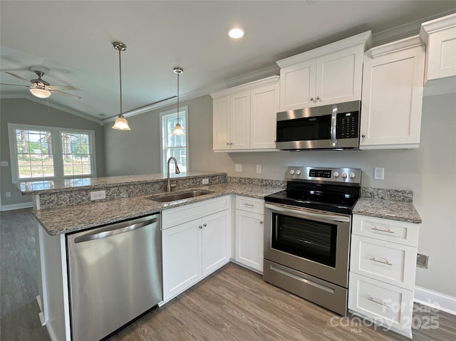 kitchen with appliances with stainless steel finishes, white cabinetry, a peninsula, and a sink