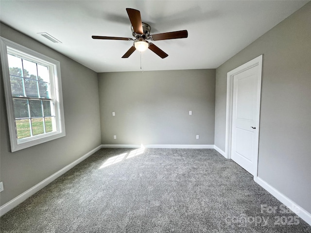 carpeted empty room with visible vents, baseboards, and a ceiling fan