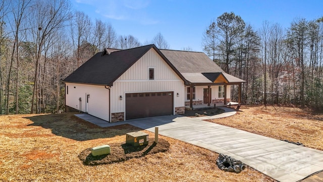 modern inspired farmhouse featuring stone siding, a porch, driveway, and roof with shingles