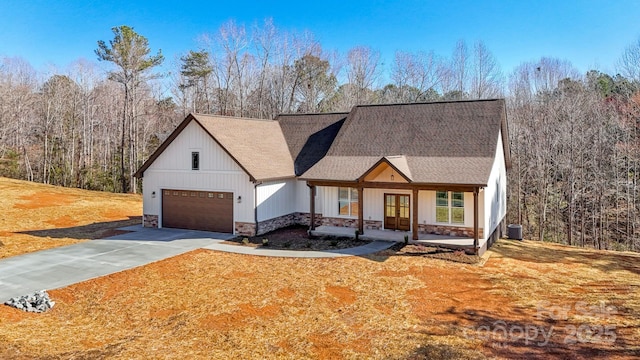 modern farmhouse style home featuring central air condition unit, driveway, stone siding, french doors, and a garage