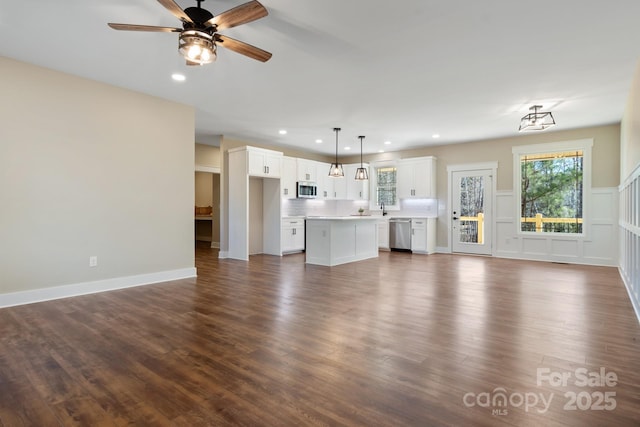 unfurnished living room with dark wood-style flooring, recessed lighting, a decorative wall, a ceiling fan, and a sink