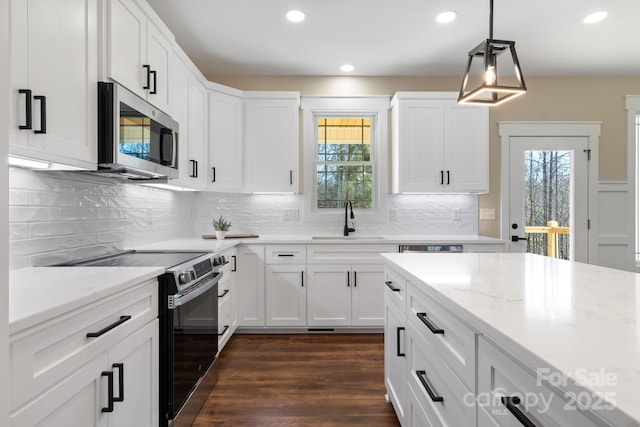 kitchen with dark wood finished floors, a sink, electric stove, white cabinetry, and stainless steel microwave