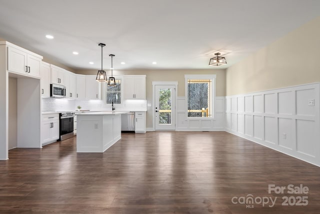 kitchen with open floor plan, backsplash, white cabinets, and stainless steel appliances