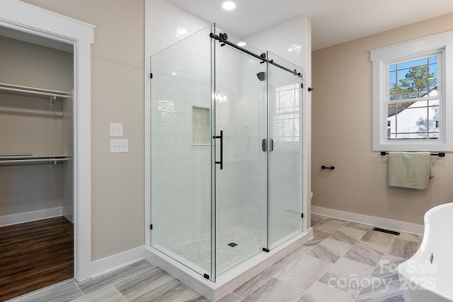 bathroom with a spacious closet, recessed lighting, a shower stall, and baseboards