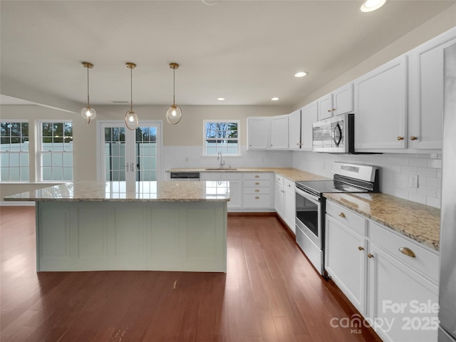 kitchen featuring a sink, dark wood finished floors, a center island, white cabinetry, and stainless steel appliances