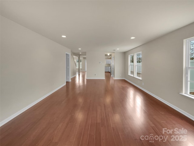 unfurnished living room with recessed lighting, wood finished floors, and baseboards