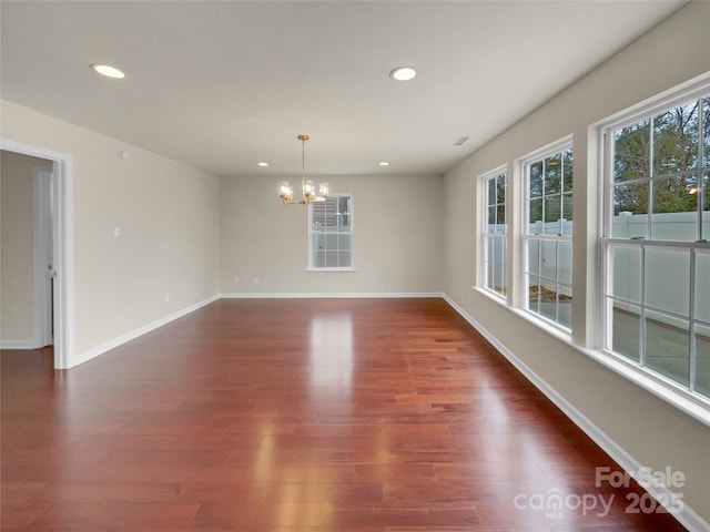 empty room featuring recessed lighting, baseboards, an inviting chandelier, and dark wood-style flooring