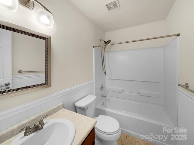 full bathroom with visible vents, toilet,  shower combination, wainscoting, and vanity